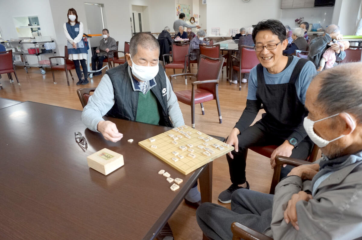 吉田武志さんが利用者様と将棋を楽しむ様子